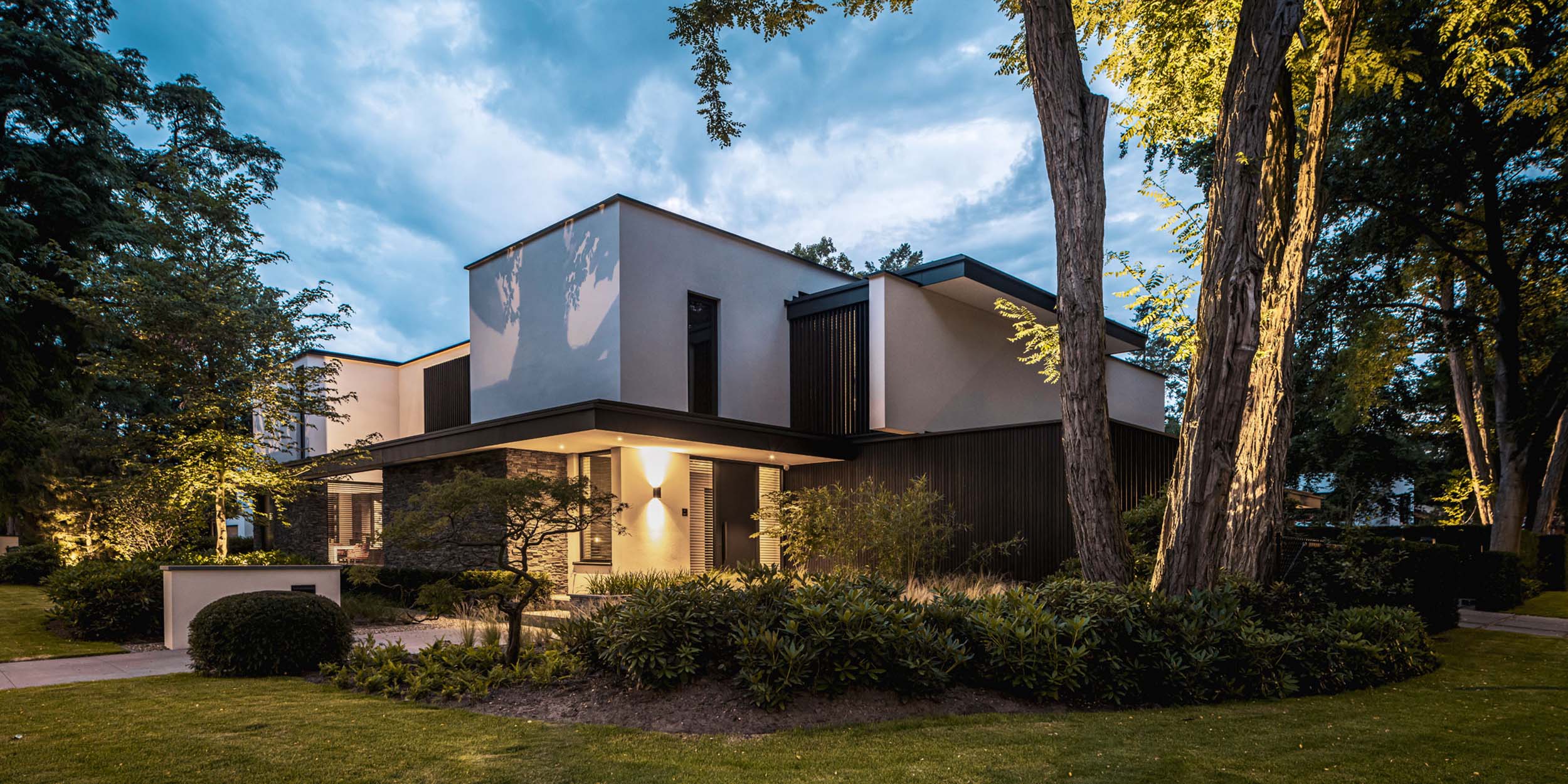 Moderne villa in bosrijke tuin tijdens avondlicht